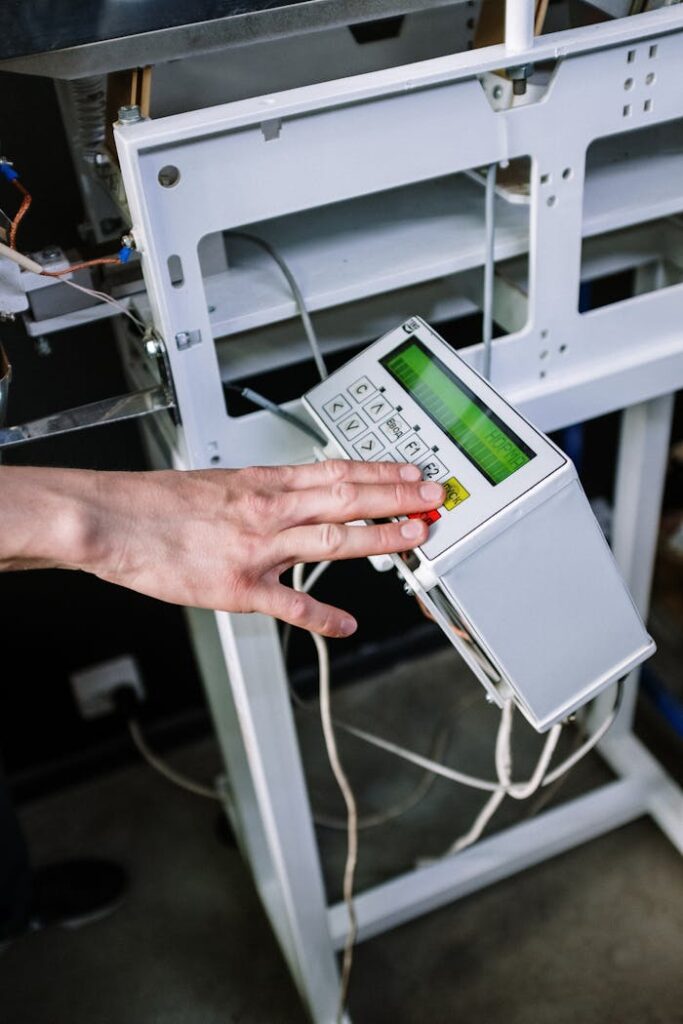 Detailed view of a person's hand operating a control panel on a coffee roasting machine.